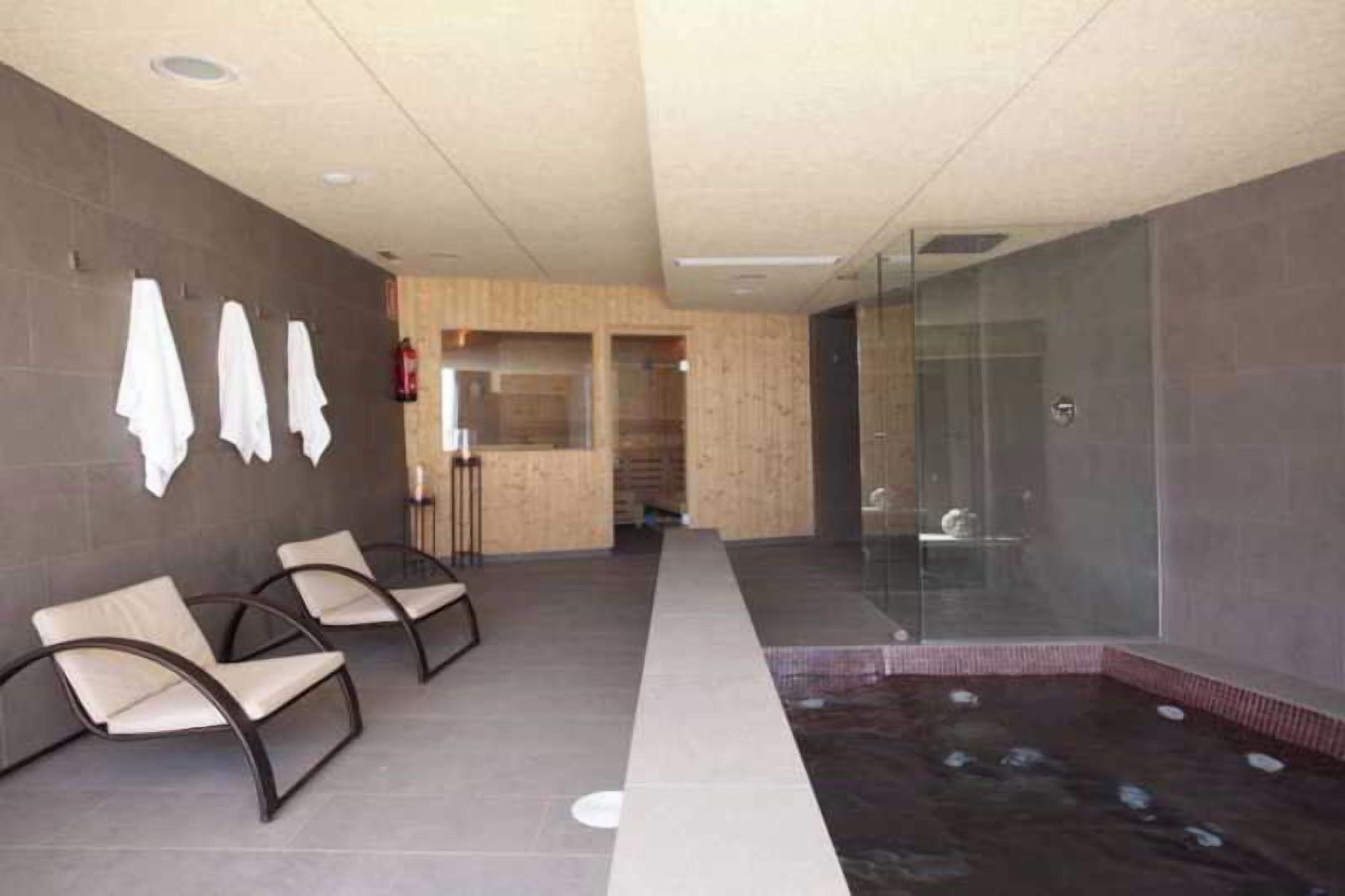 A spa area with seating, a hot tub, and a glass shower enclosure.