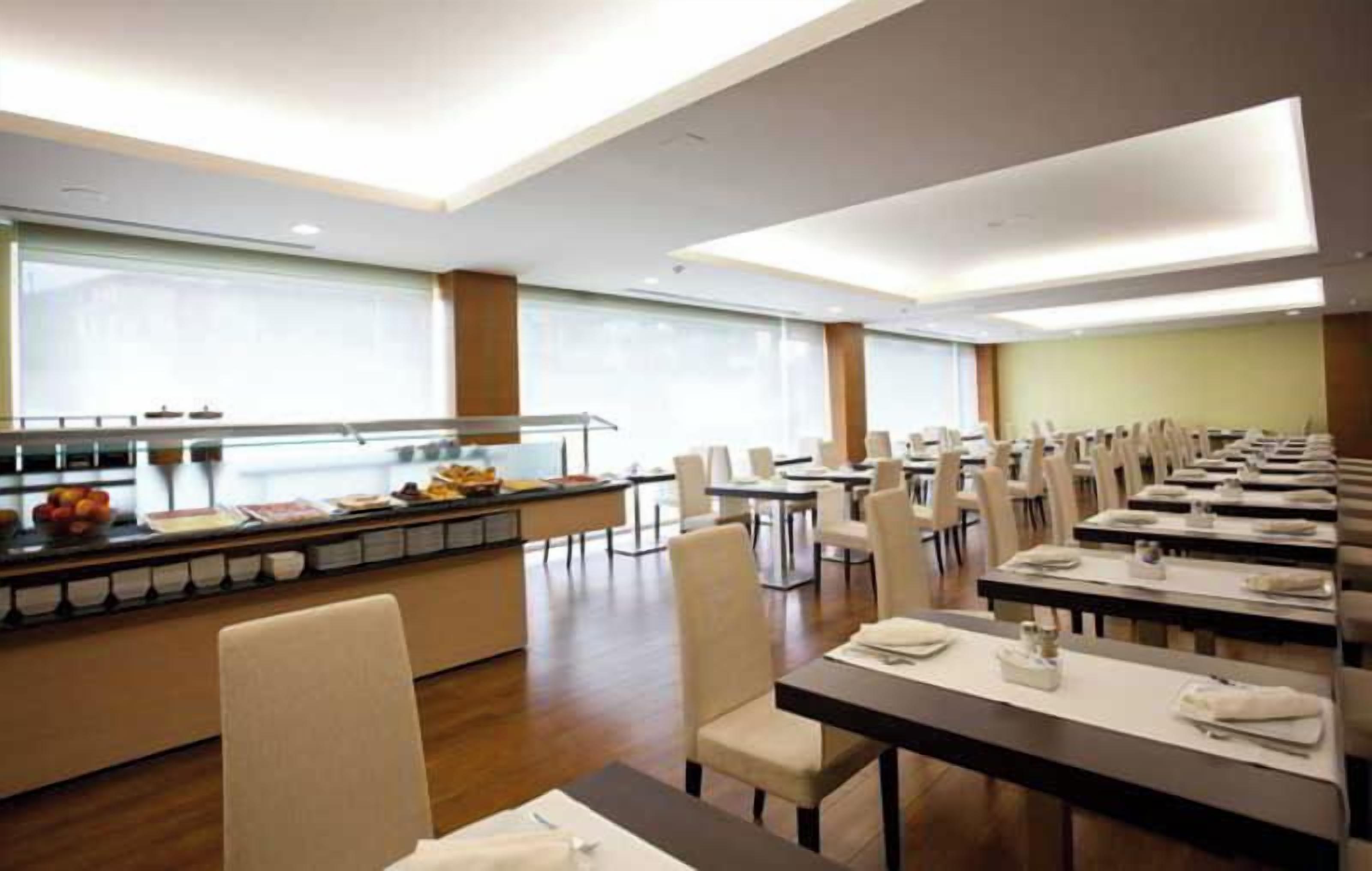 Un espace de restauration d’hôtel avec un buffet et plusieurs tables.