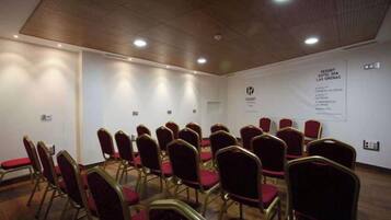 Un salón de conferencias con filas de sillas y una pizarra en la pared.