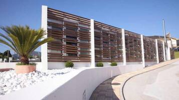 Un edificio moderno con fachada blanca, un sendero curvo y una palmera.