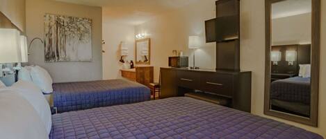 Quarto de hotel com duas camas, uma escrivaninha, cómoda, espelho e obras de arte na parede.