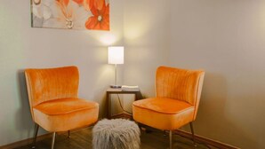 Two orange chairs facing each other with a small table and a lamp between them. - Shady Acre Inn and Suites (Branson West)