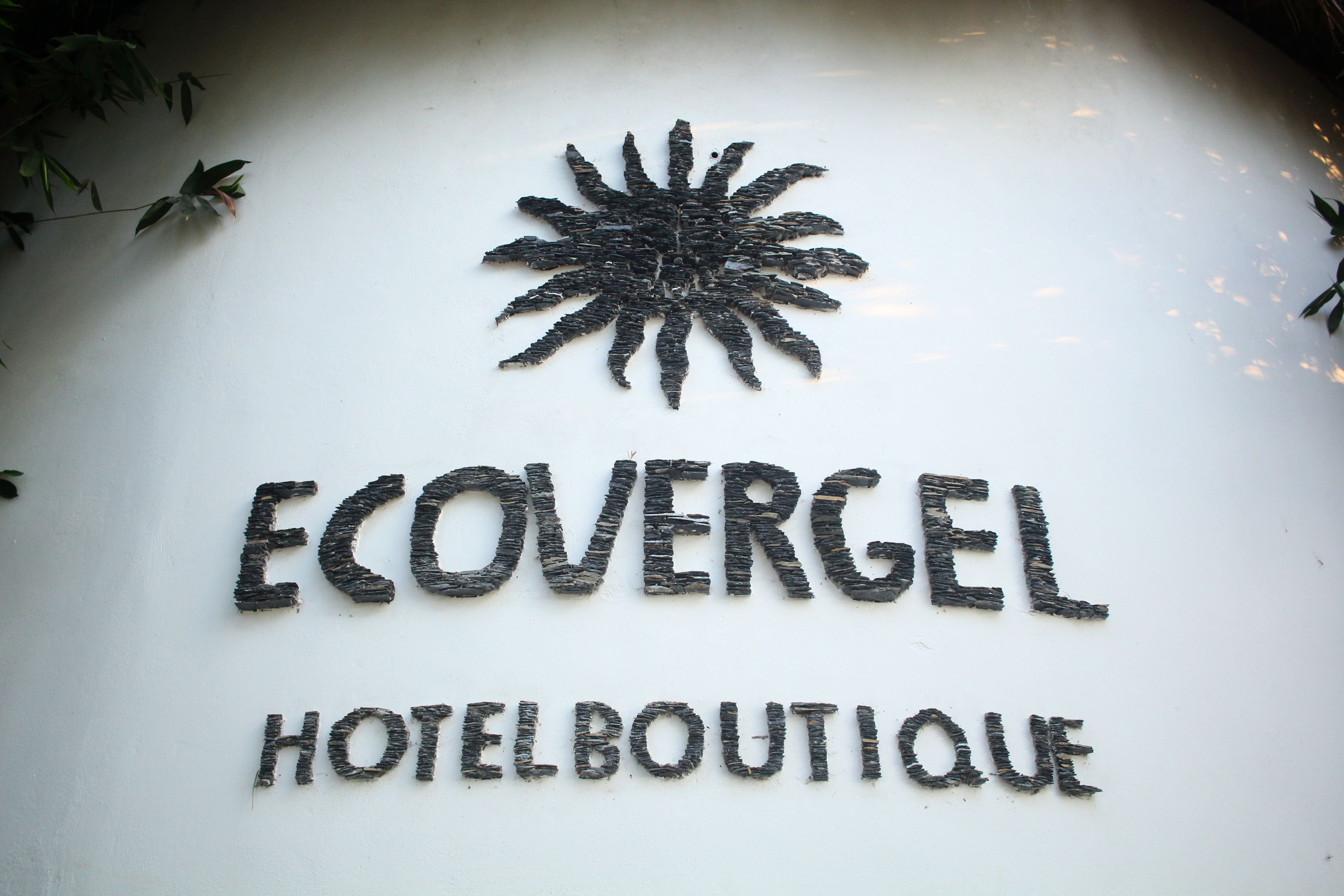 Segnaletica per l'Ecovergel Hotel Boutique con un design simile a un sole sopra il testo.
