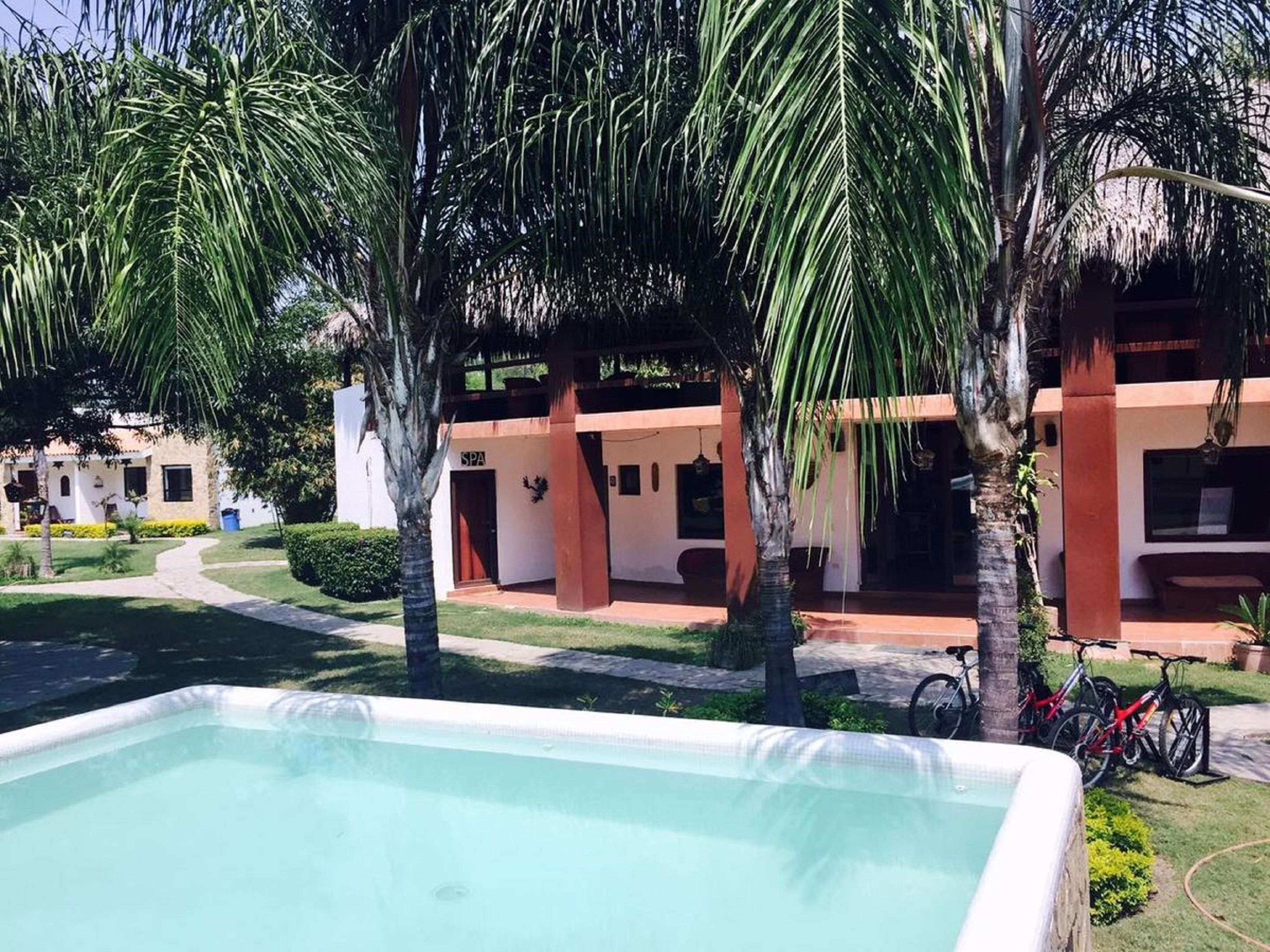A pool area with a spa building, palm trees, and bicycles.