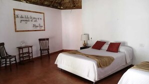 Een slaapkamer met een bed, twee stoelen, een nachtkastje en een muisbrief.