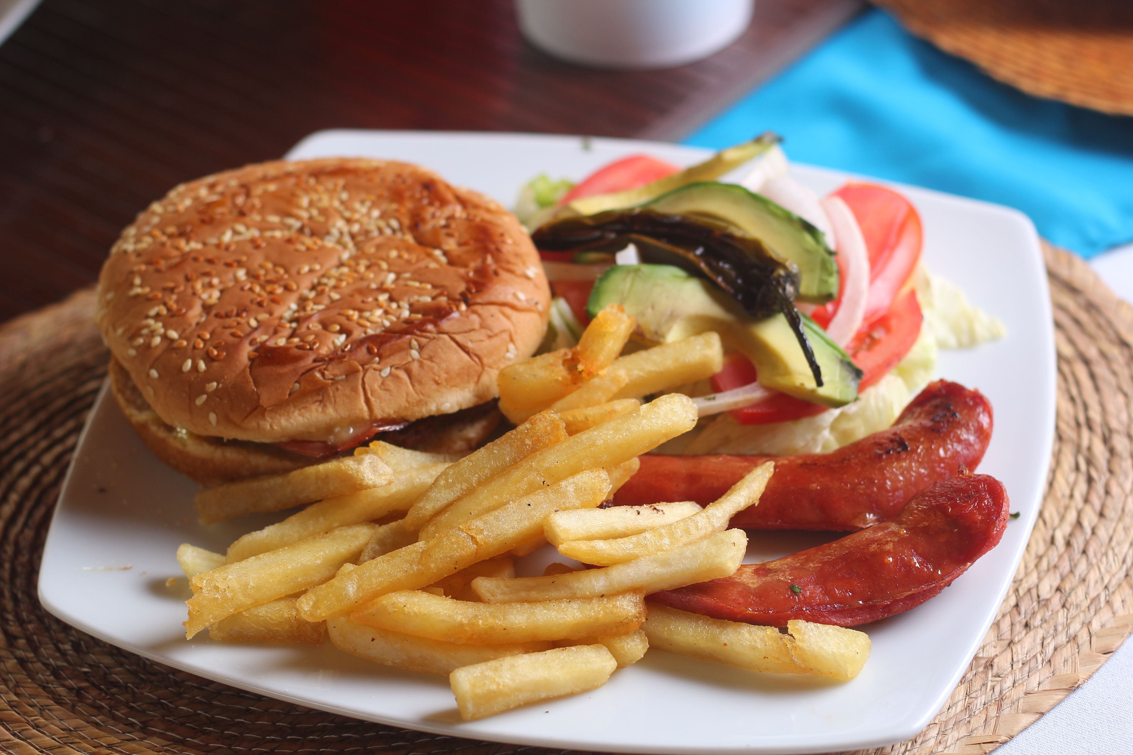 A plate with a hamburger, fries, and sausages.