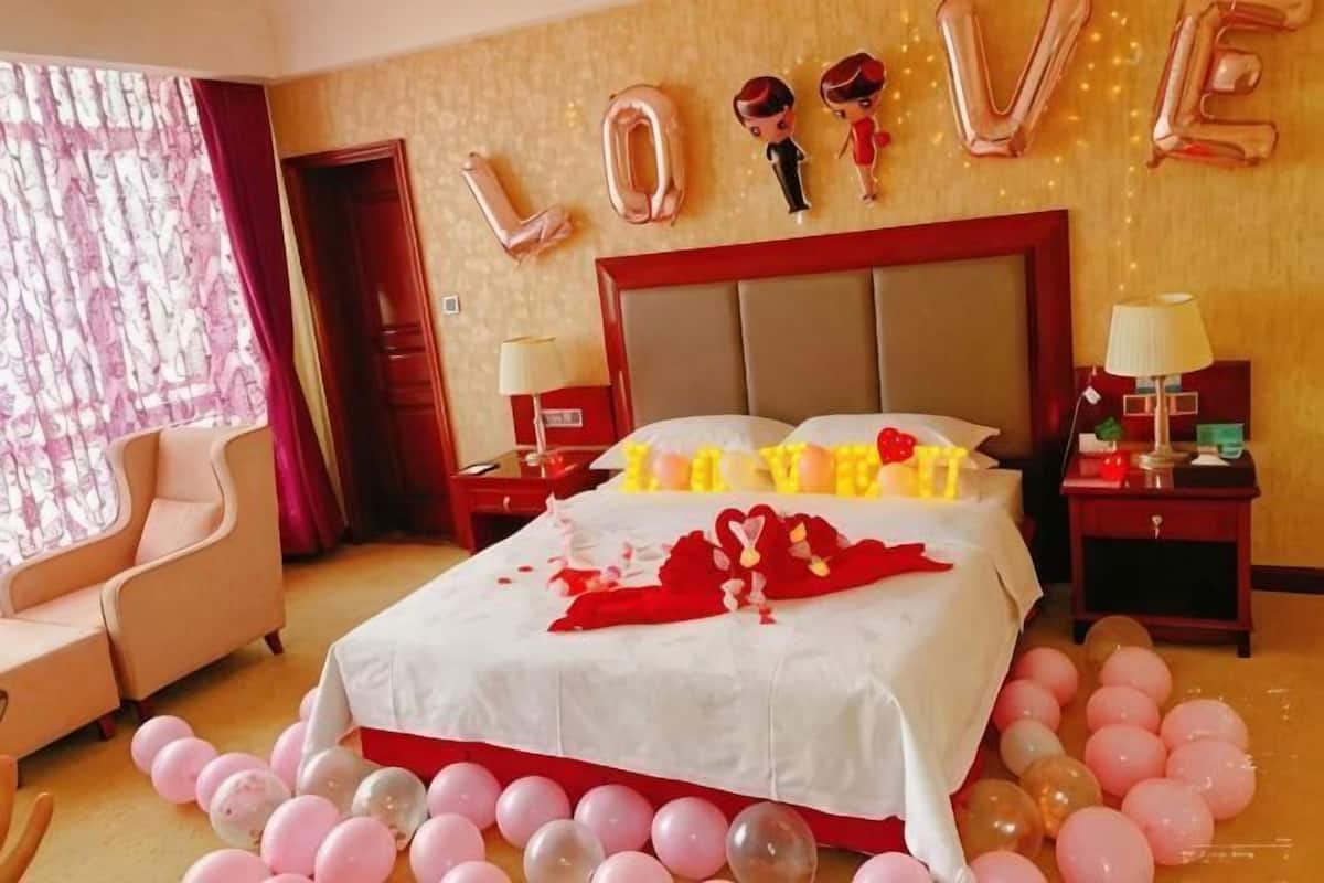 A hotel room with a large bed, two bedside tables, a chair, and a window with curtains.