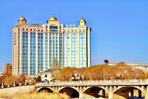 A multi-story building with a prominent entrance and a bridge in the foreground. - Mengguzhen Hotel (Fuxin)