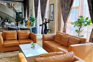 A lobby with leather sofas, a coffee table, and a staircase. - Mengguzhen Hotel (Fuxin)