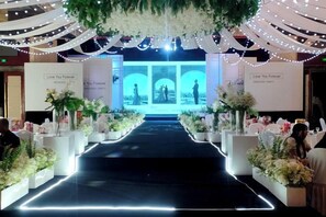 A wedding aisle with floral arrangements and a stage for the ceremony. - Mengguzhen Hotel (Fuxin)
