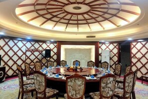 A conference room with a round table, chairs, and a decorative ceiling. - Mengguzhen Hotel (Fuxin)