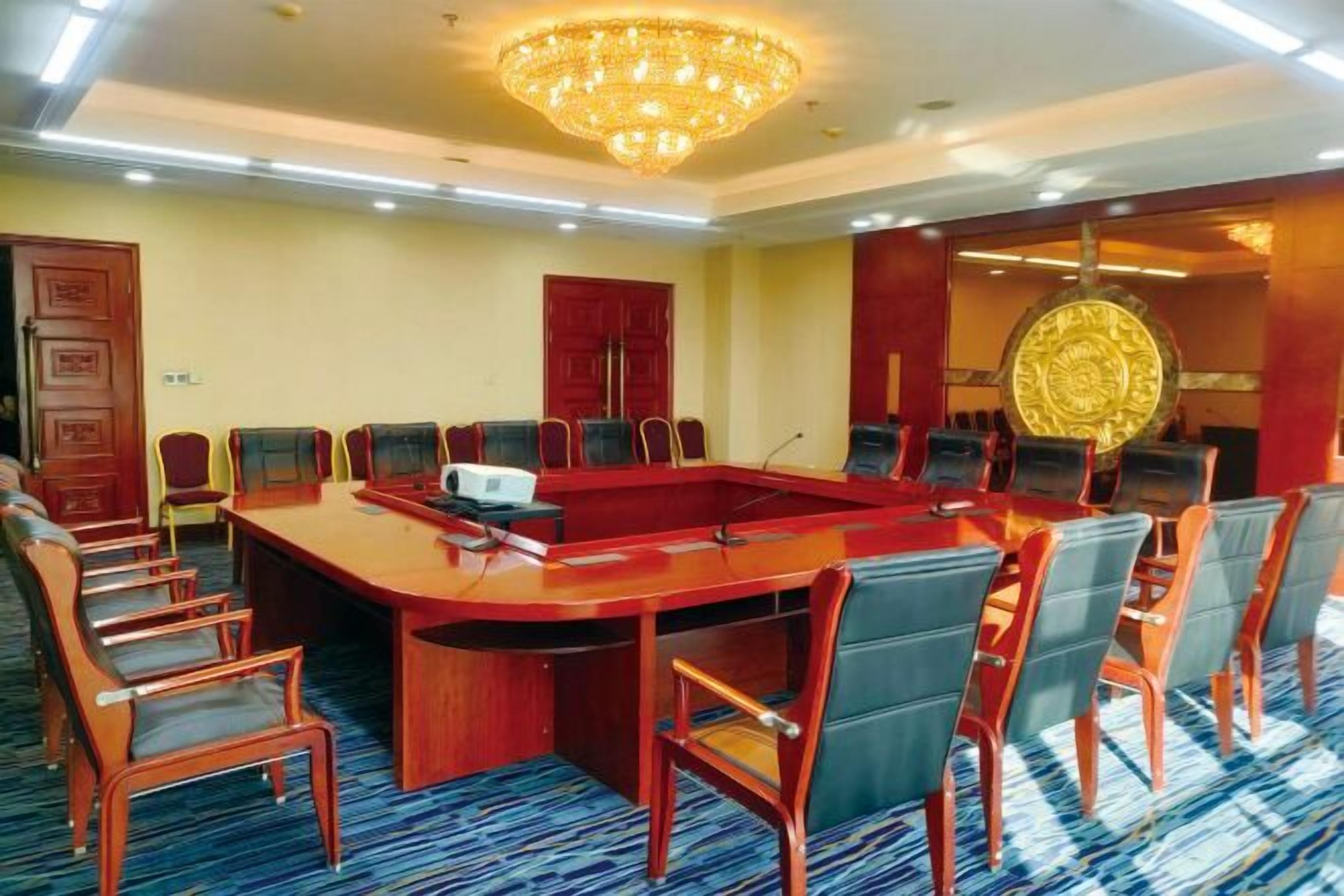 A conference room with a large oval table, multiple chairs, and a chandelier.