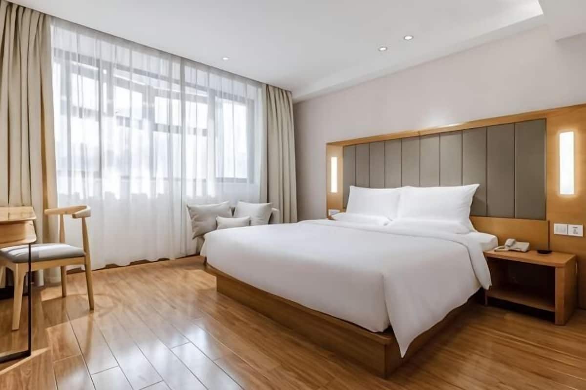Ein Hotelzimmer mit einem großen Bett, einem Schreibtisch, einem Sessel und einem Nachttisch mit Telefon.