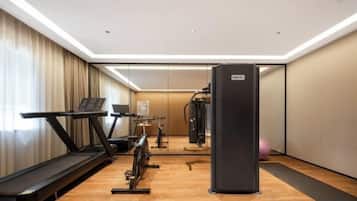 Une salle de sport d’hôtel équipée d’un tapis de course, d’un vélo d’appartement et d’une machine de musculation.