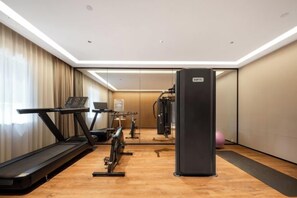 A hotel gym with a treadmill, stationary bike, and weight machine.