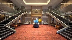 A spacious lobby with a geometric patterned carpet, a central round table with a sculpture, and two staircases on either side. - Huhua International Hotel (Shanghai Wujing Hua Normal University Branch) (Shanghai)