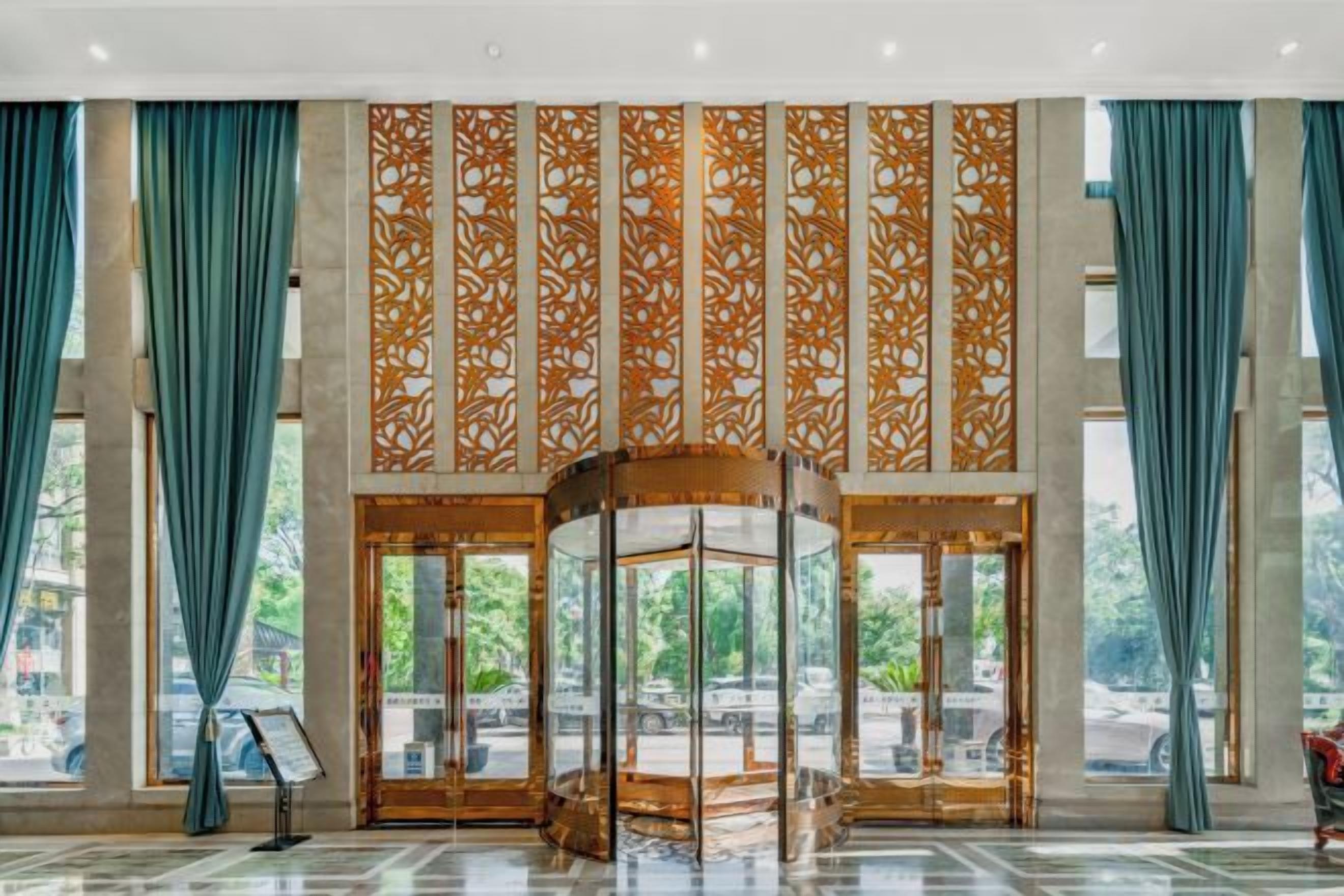 A hotel lobby with a revolving door, large windows, and a decorative panel.