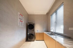 A compact kitchen with a built-in washer and dryer, a window with blinds, and a sink. - Huhua International Hotel (Shanghai Wujing Hua Normal University Branch) (Shanghai)