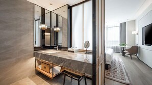 Une salle de bain moderne avec un grand miroir, deux vasques et un banc.