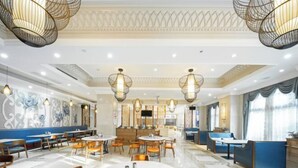 A spacious dining area with round tables and chairs, decorative wall panels, and hanging light fixtures. - Huhua International Hotel (Shanghai Wujing Hua Normal University Branch) (Shanghai)
