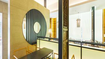 A modern interior with a dining area, a large circular mirror, and a staircase.