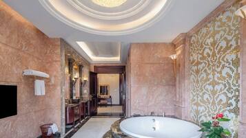 A luxurious bathroom with a large freestanding bathtub, marble walls, and a chandelier.
