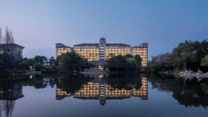 Un hotel grande e iluminado, con fachada simétrica y reflejo en el agua.