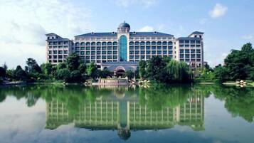Stunning hotel with a central dome and balconies, situated beside a serene body of water.