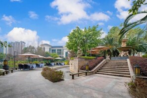 An outdoor patio area with seating, a fountain, and a staircase leading to a higher level. - Evergrande World MICE Center (Jintang)