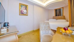 A hotel room with a bed, a chair, a desk with a kettle, and a fruit bowl. - Vienna International Hotel (Shenzhen Xiashuijing Metro Station) (Shenzhen)