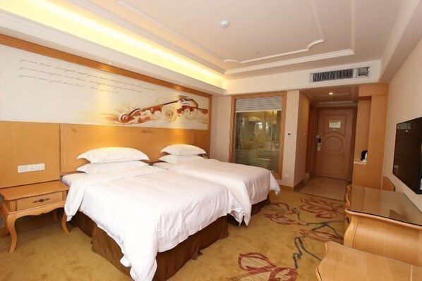 A hotel room with two beds, a desk, a TV, and a large painting on the wall. - Vienna International Hotel (Shenzhen Xiashuijing Metro Station) (Shenzhen)