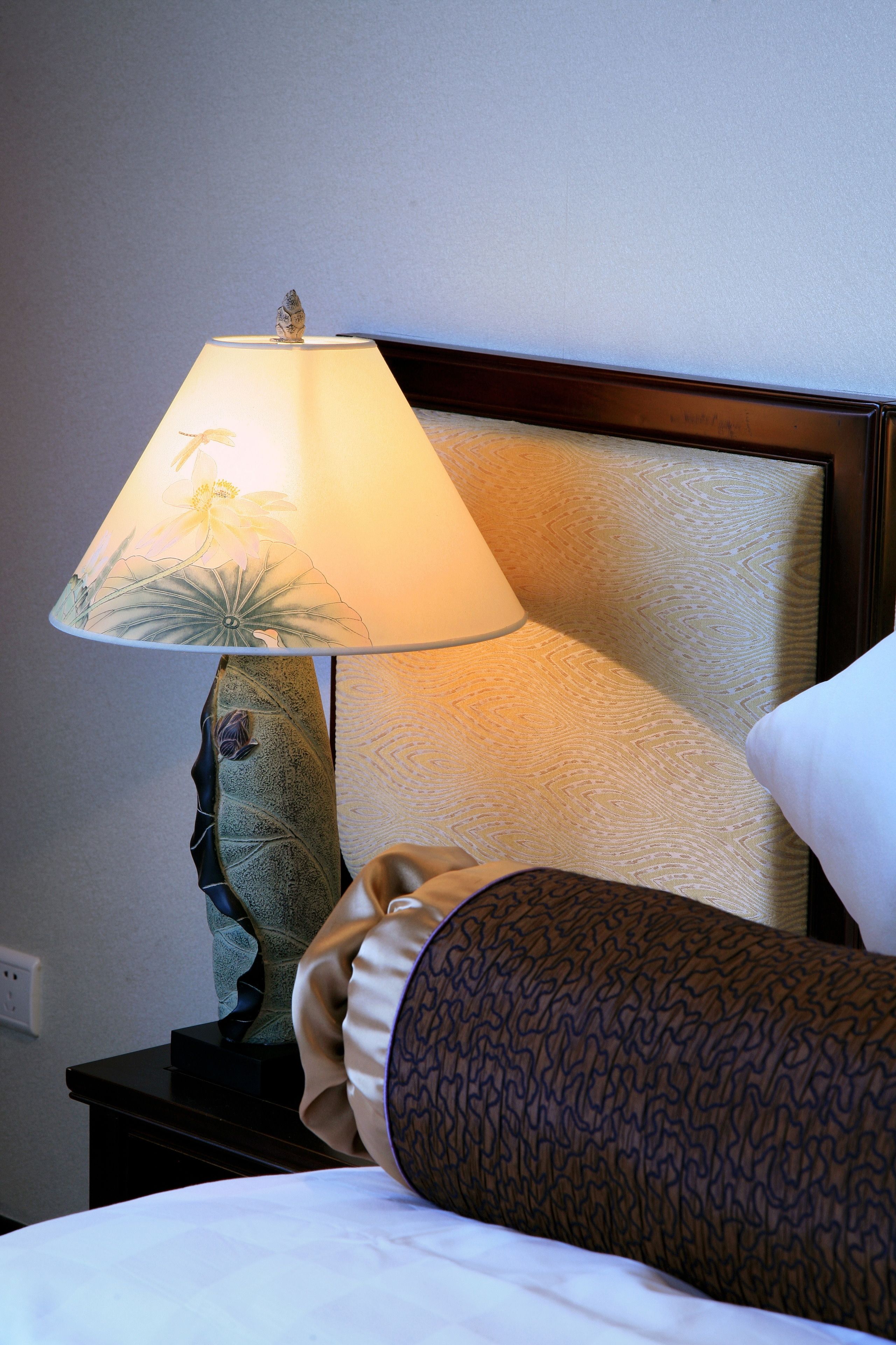 Ein Hotelzimmer mit einem Bett, einem Nachttisch mit einer Lampe und einem Kissen.