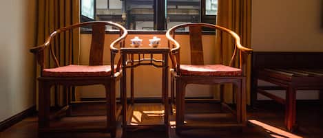 Una mesa de madera tradicional con dos sillas en una habitación con suelo de madera y una ventana con cortinas.