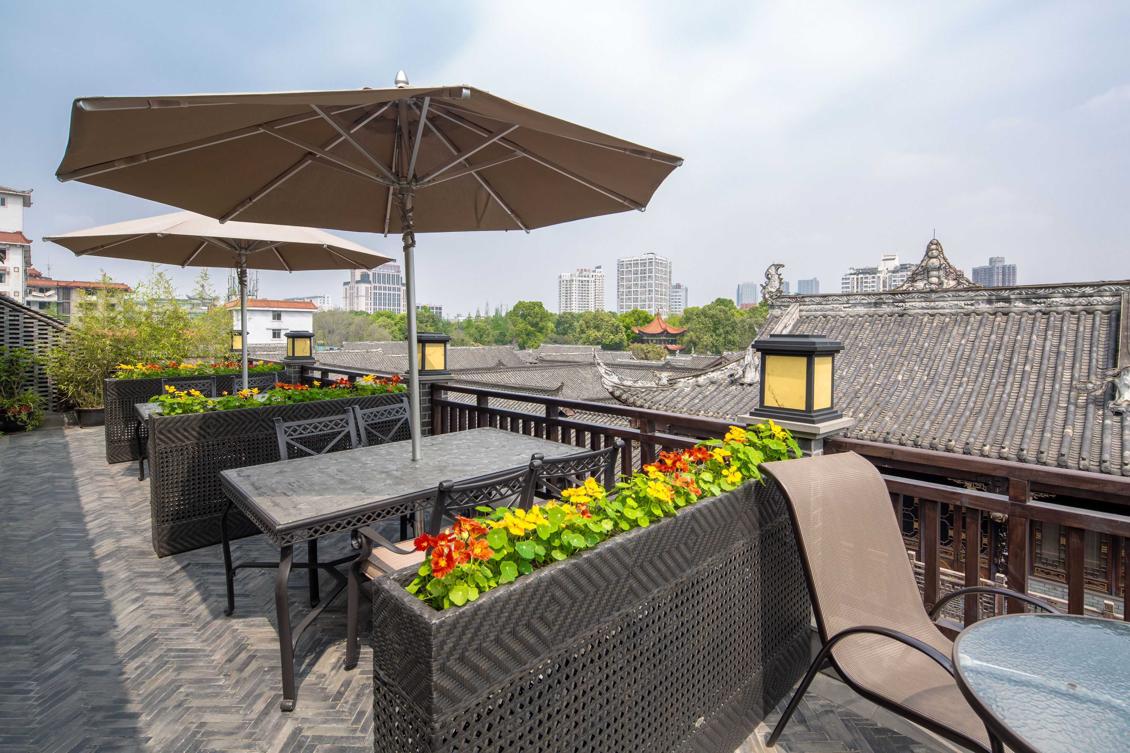 Un patio al aire libre con mobiliario de mimbre, sombrillas y vistas a arquitectura tradicional.