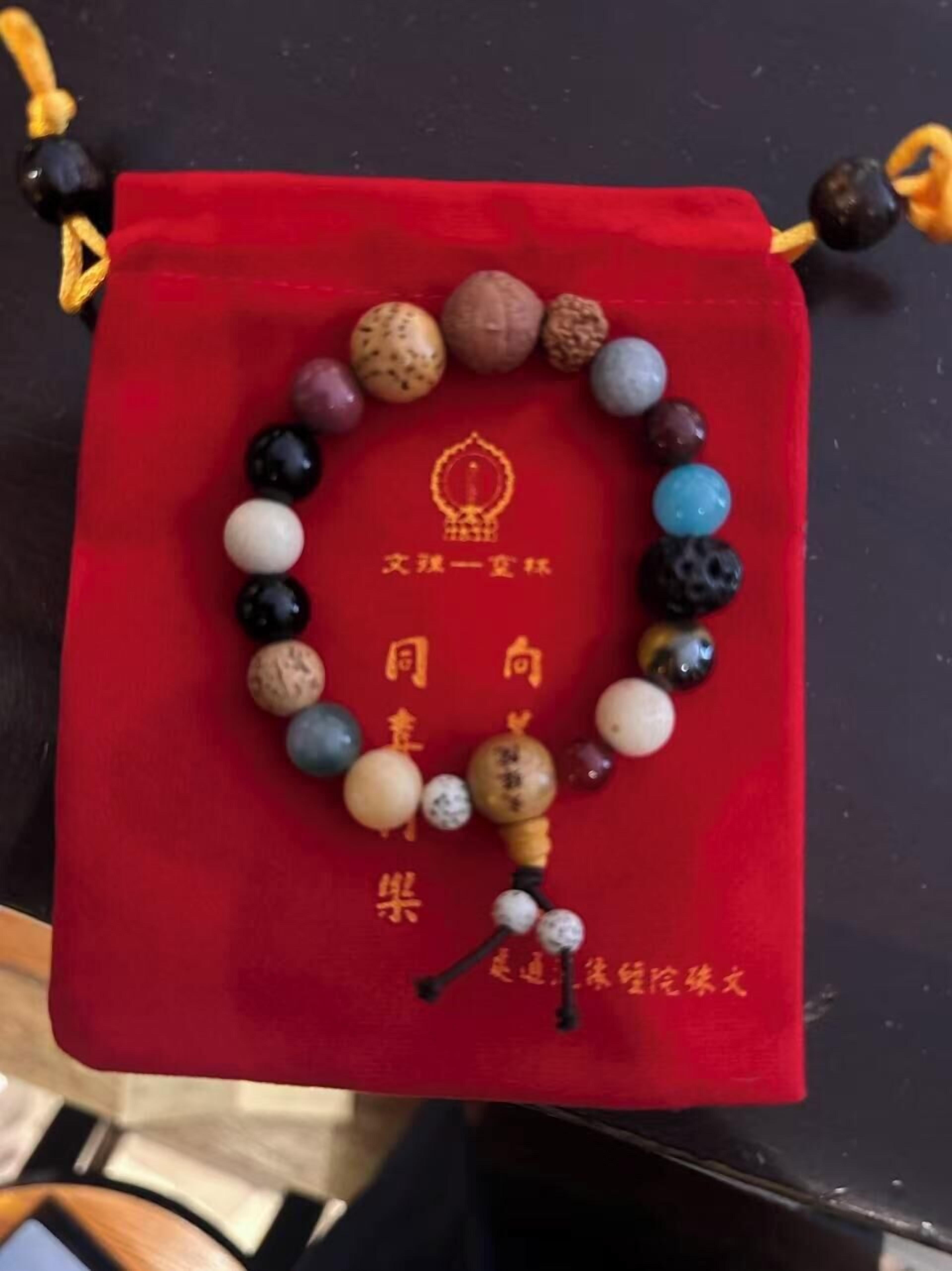A red velvet box with a beaded bracelet and Chinese characters.