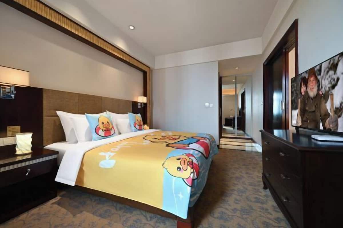 A hotel room with a large bed, a nightstand, a dresser, and a painting on the wall.