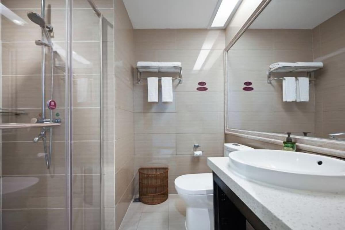 A modern bathroom with a glass shower enclosure, a white sink, and a toilet.