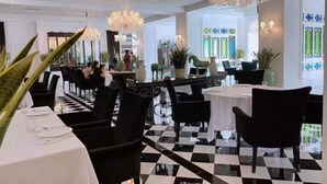 A restaurant with black and white checkered flooring, black chairs, white tables, and chandeliers. - Agile Hotel (Zhongshan)
