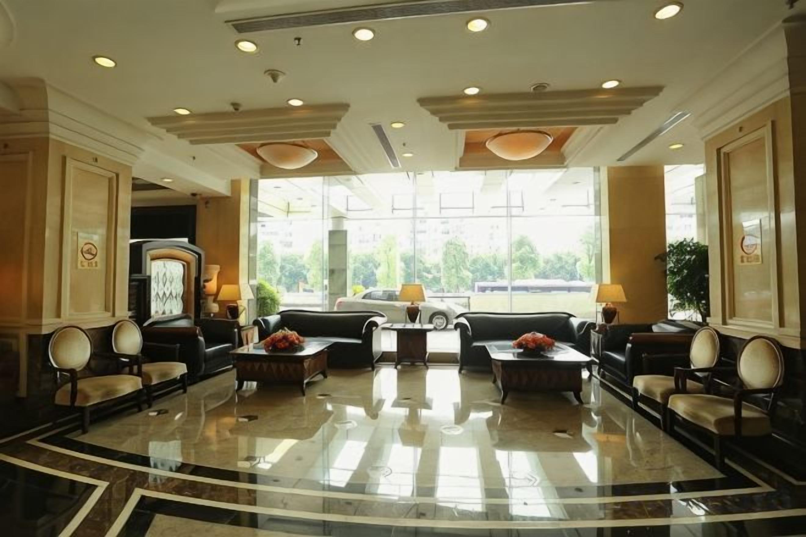 A hotel lobby with a marble floor, seating area, and large windows.