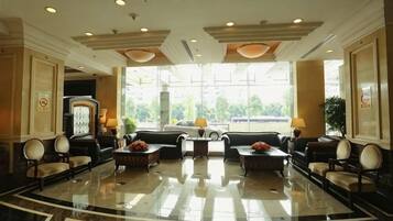 A hotel lobby with a marble floor, seating area, and large windows.