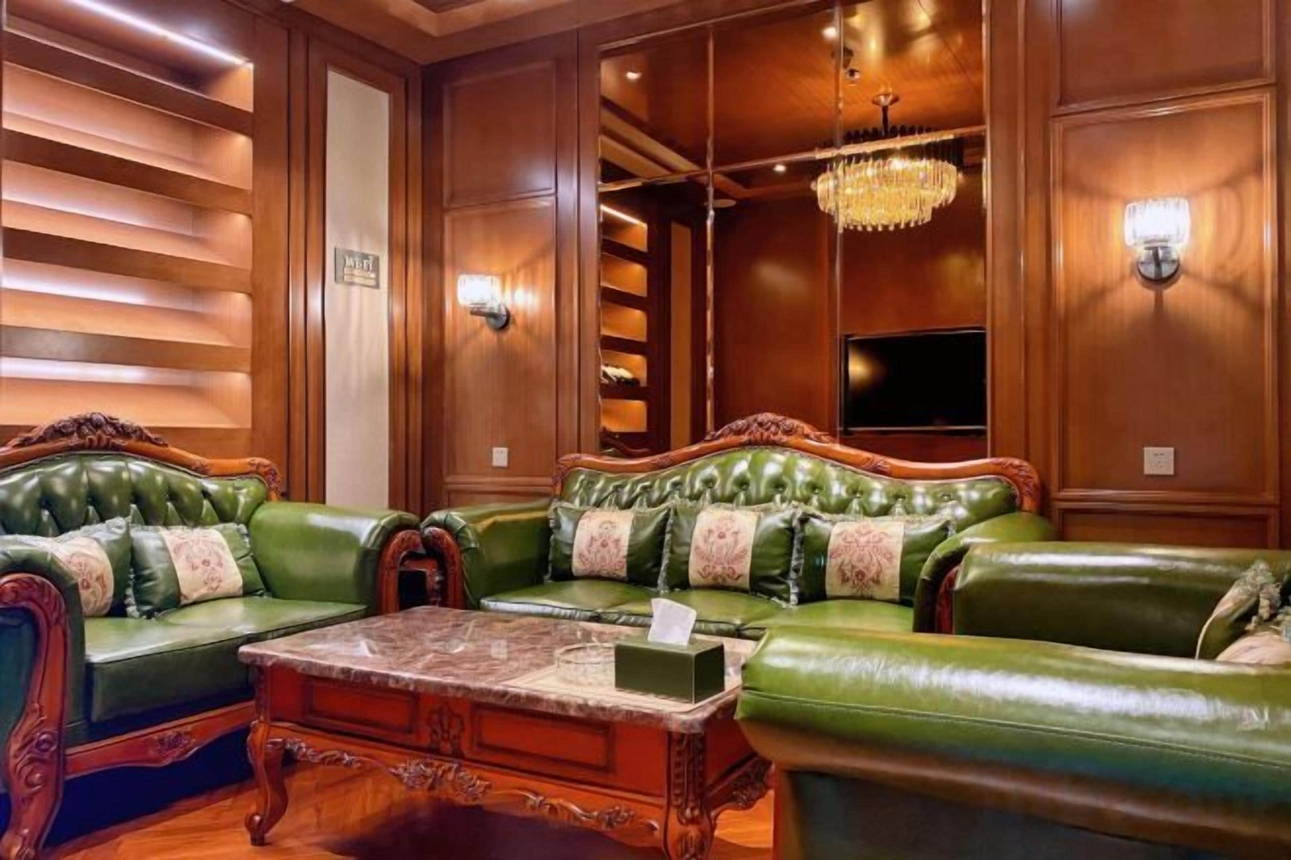 A green leather sofa set with a marble coffee table, wooden paneling, and wall sconces.