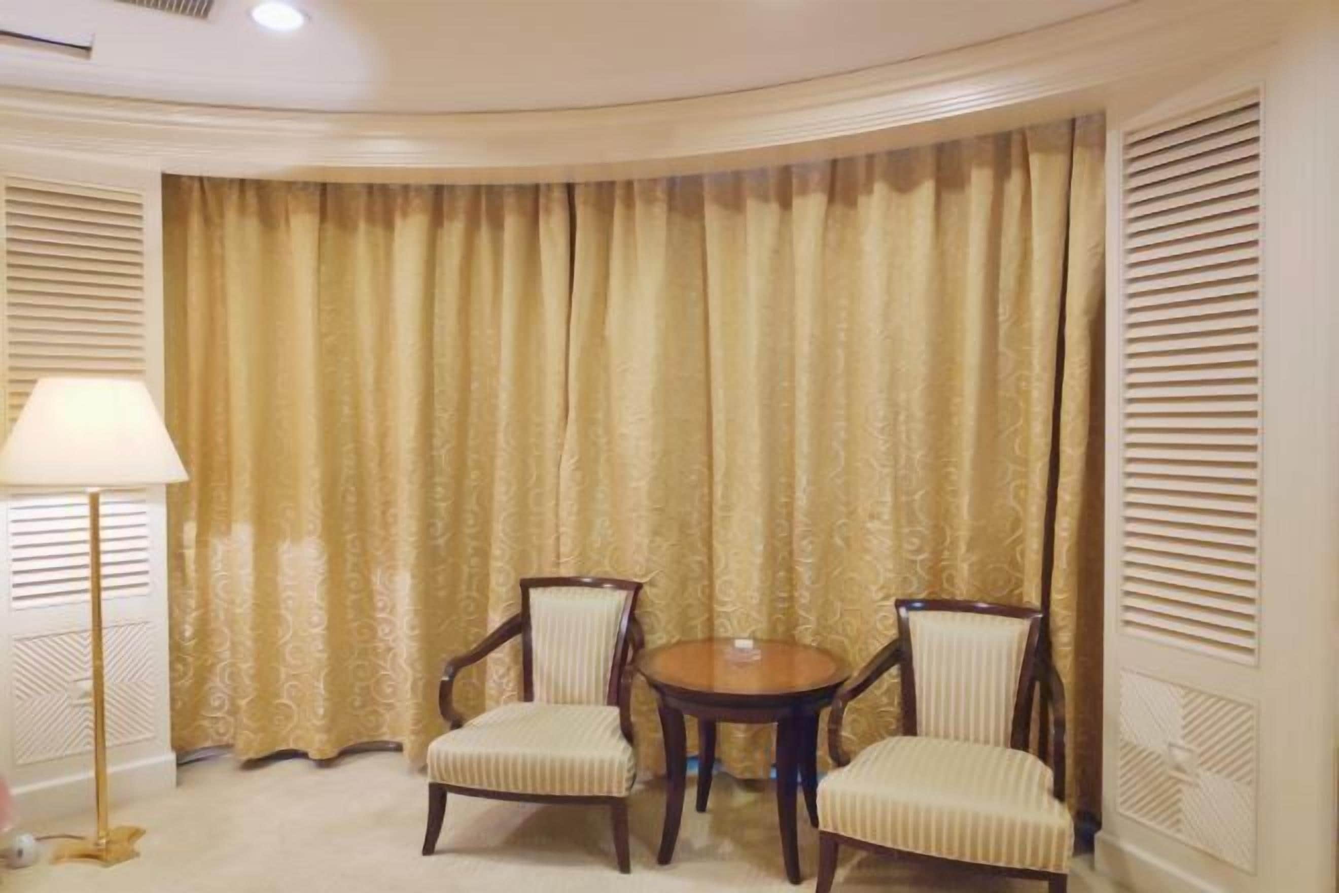 A corner room with two upholstered chairs, a small round table, and a floor lamp.
