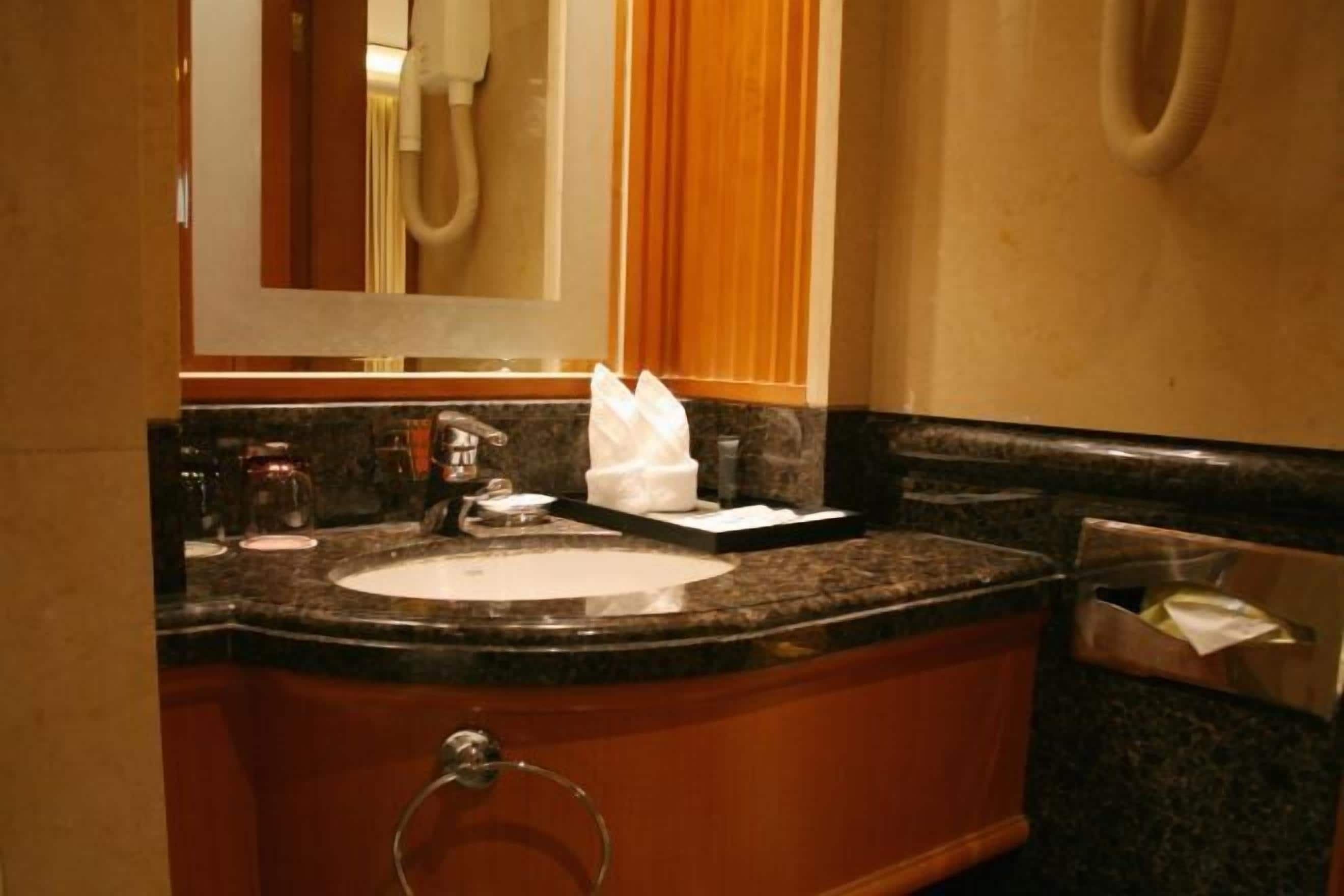 Un baño con lavamanos, espejo y toallero.