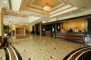 A hotel lobby with a reception desk, a large chandelier, and a marble floor. - Agile Hotel (Zhongshan)