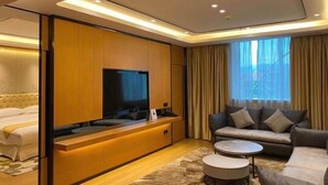 A modern hotel room with a bed, a sofa, a TV, and a large window with curtains. - Agile Hotel (Zhongshan)