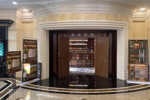 A hotel lobby with a bar area, a reception desk, and a display of wine bottles. - Agile Hotel (Zhongshan)