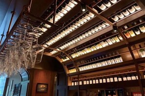 A wine cellar with shelves of bottles and a hanging light fixture. - Agile Hotel (Zhongshan)