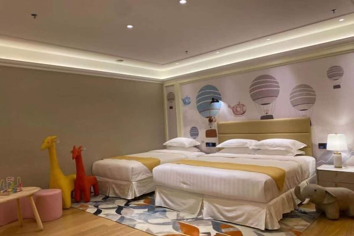 A hotel room with two beds, a small table, and a nightstand.