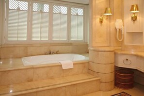 A bathroom with a large bathtub, a vanity with a mirror, and a telephone. - Agile Hotel (Zhongshan)