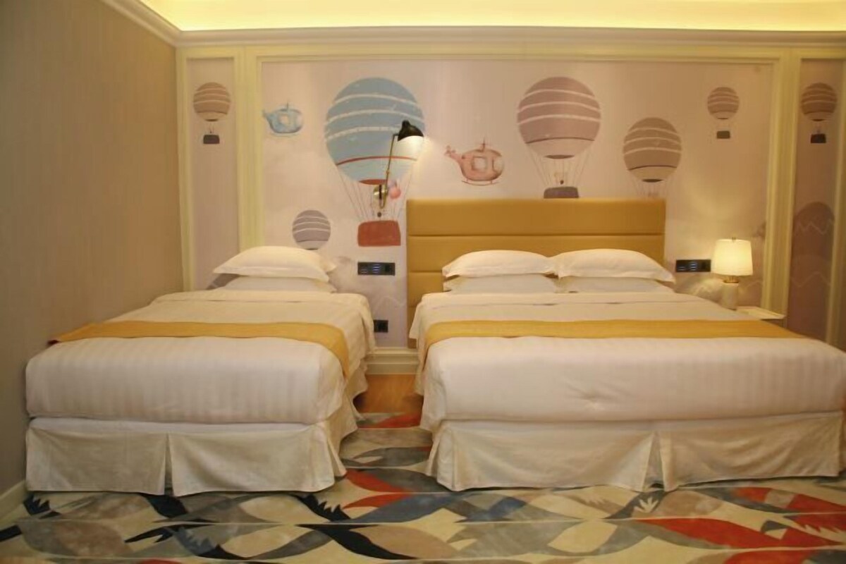 A hotel room with two beds, a patterned floor, and a wall decorated with hot air balloon designs.